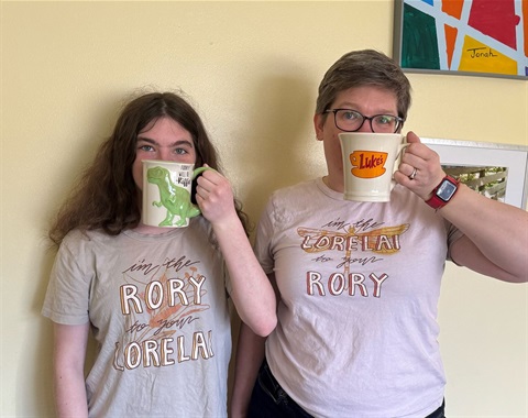 Kara and her daughter are wearing coordinating Gilmore Girls t-shirts, with mugs in their hands.
