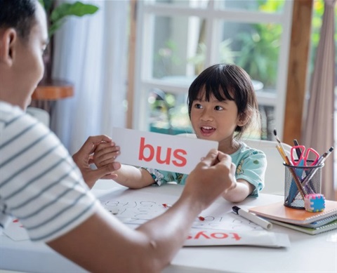 Parent and child working on reading consonant vowel consonant words using a flash card with the word 